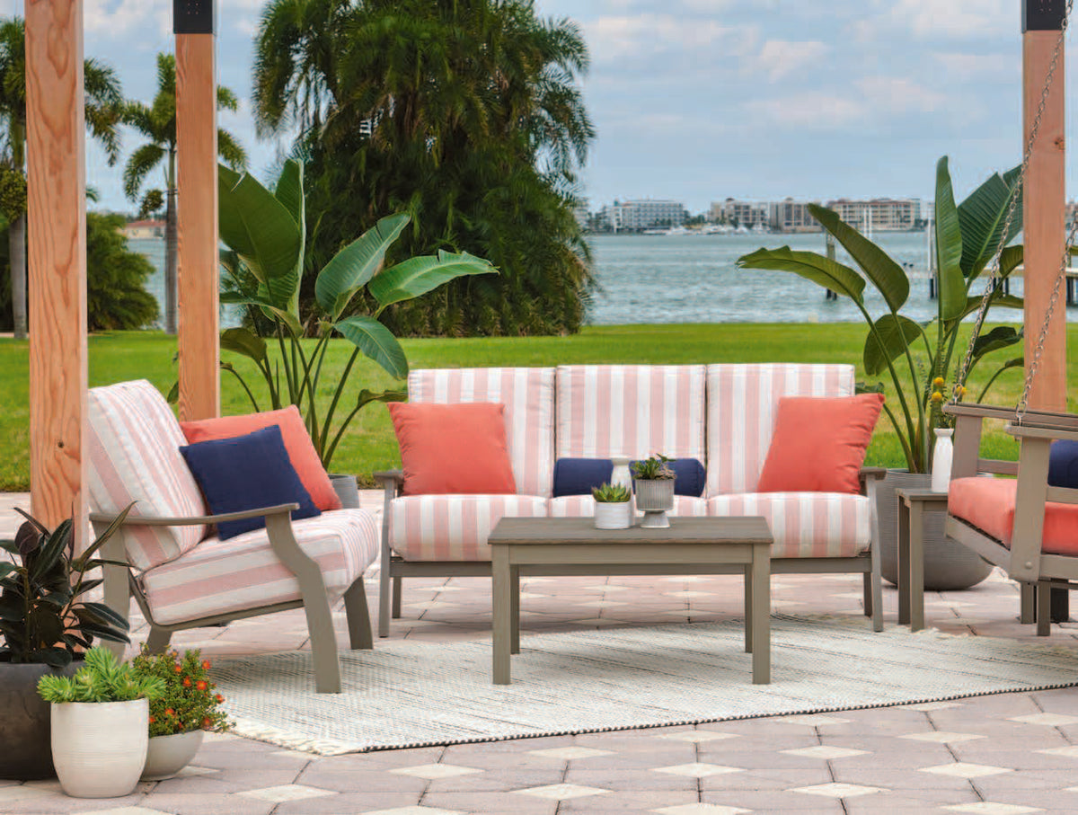 An outdoor furniture set on a stone patio with a couch, chair, and swing loveseat with matching striped cushions.